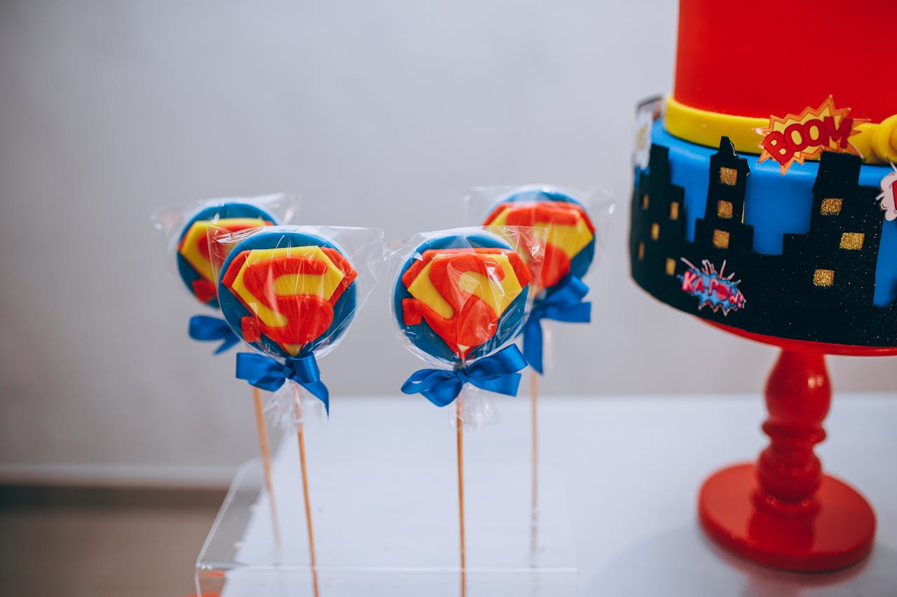 Vibrant superhero themed lollipops and cake creating a festive and fun atmosphere.