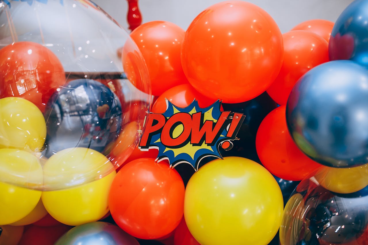 Colorful balloons surrounding a comic-style 'POW!' decoration, creating a lively atmosphere.