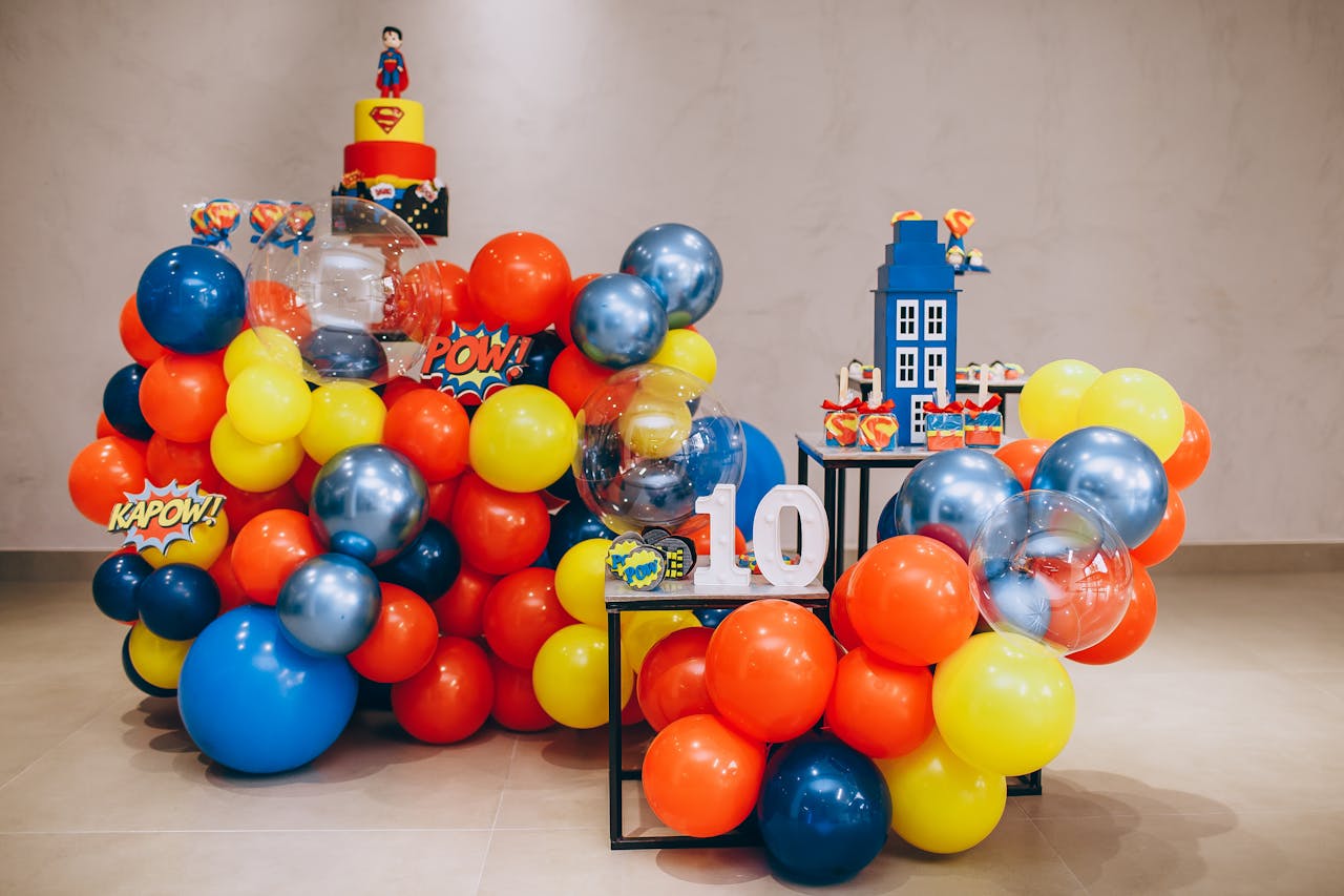 Colorful superhero themed birthday party decoration with balloons and cake.